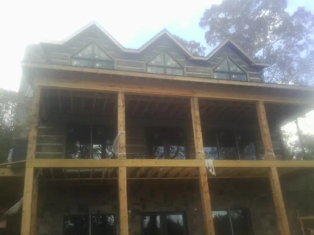 Dormers and porch framing on a large log home under construction — Roof Coating work by our crew in Artesia