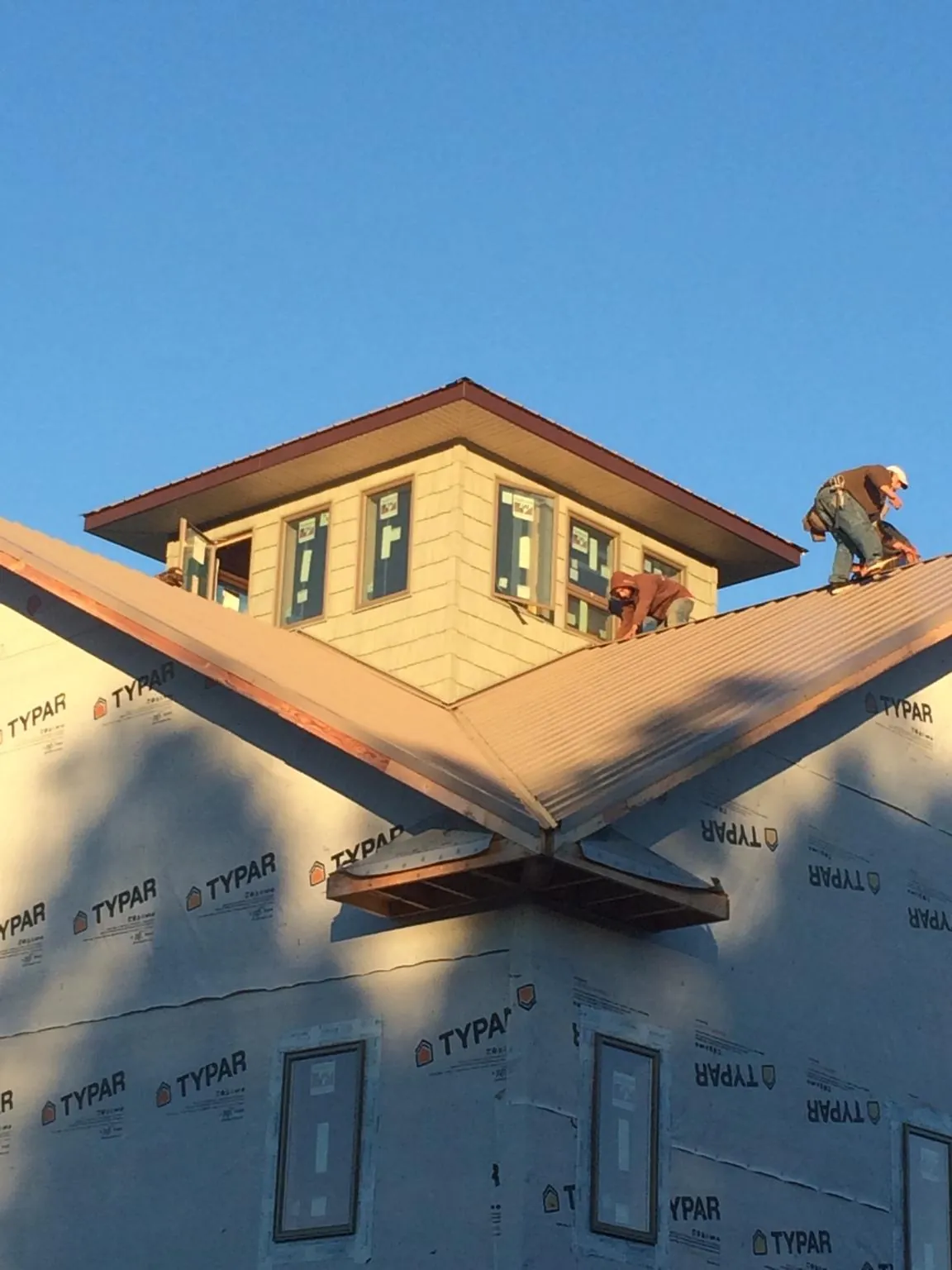 Roofers working around a rooftop cupola on a new metal roof at sunset — Roof Waterproofing in Artesia by Roofing Brothers